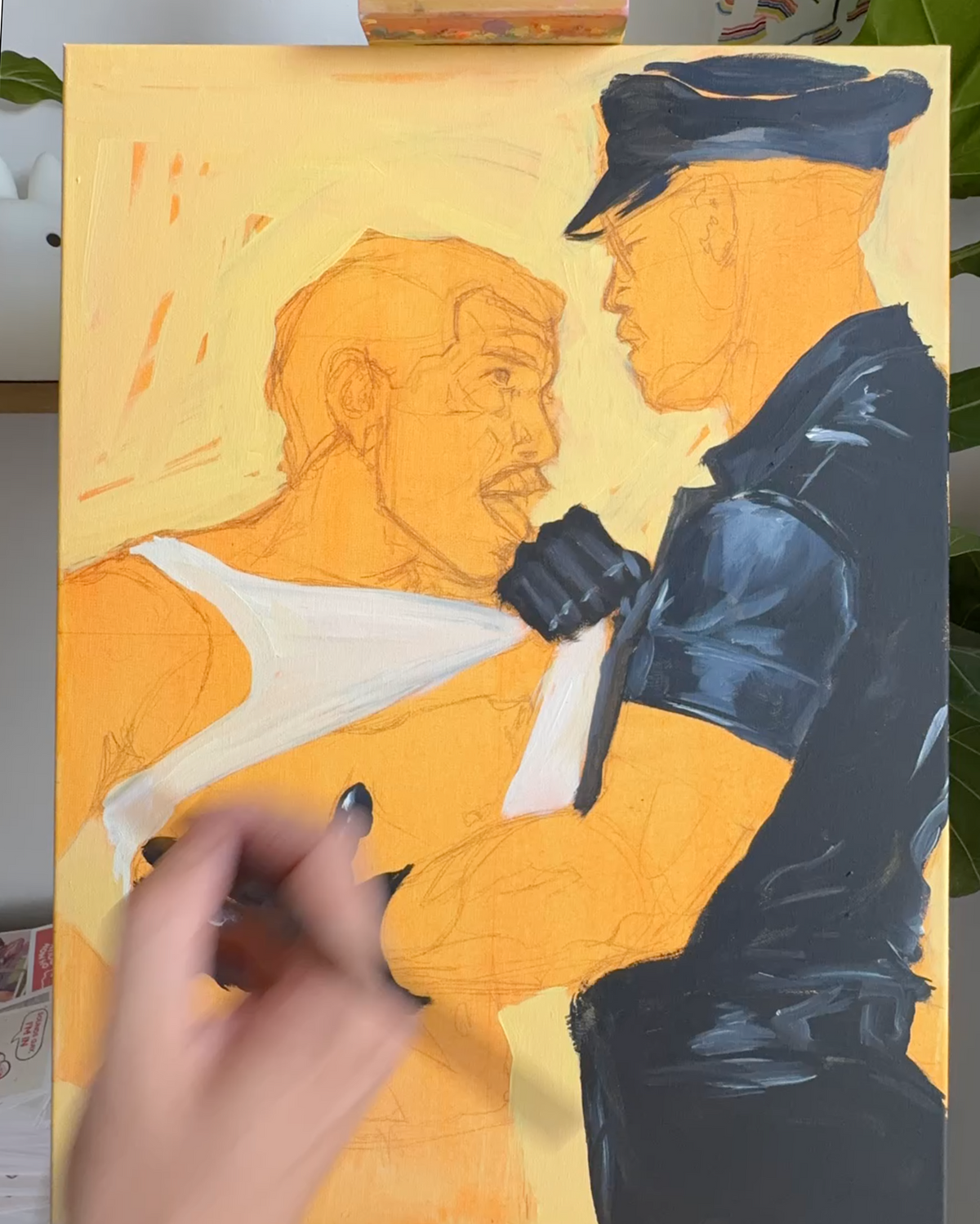A hand is painting over a portrait of a man and a police officer on a canvas. The painting features a warm yellow-orange skin tone and background, with the officer painted in dark blue-black tones.