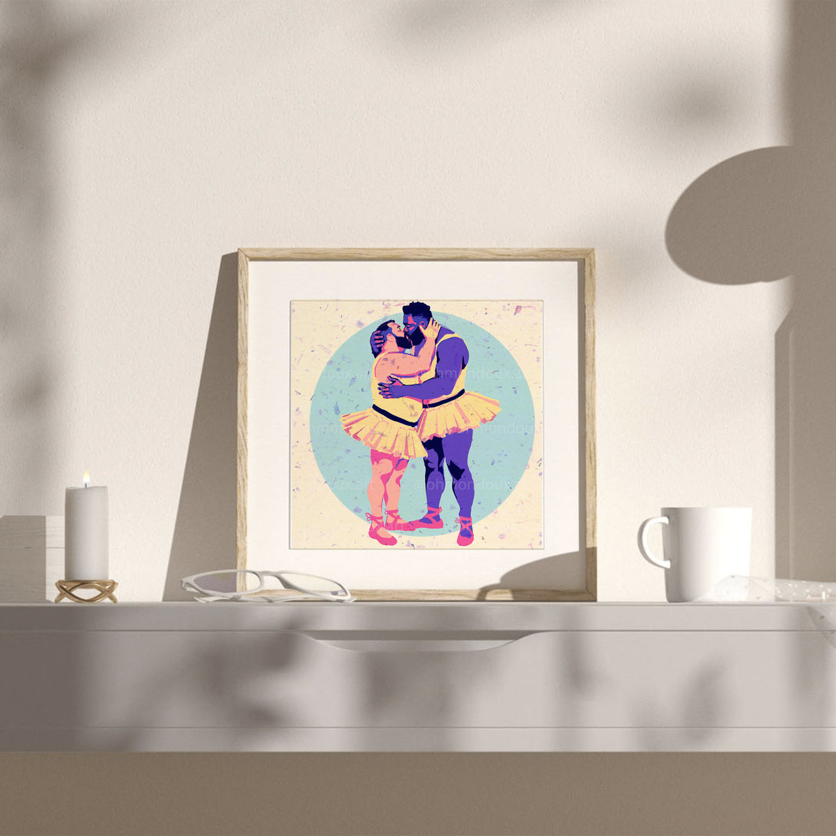 On s'en ballet couilles print framed on a white shelf next to a mug
